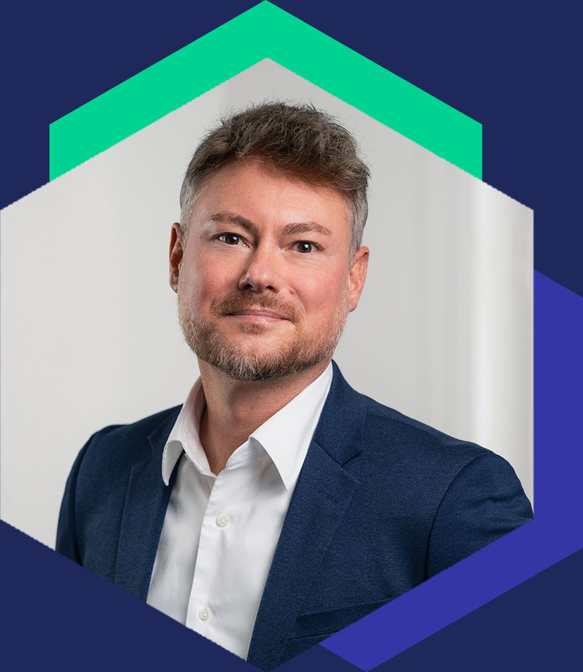 Porträt von Mathias Rentsch m blauen Sakko und weißem Hemd, dargestellt in einem hexagonalen Grafik-Element, Senior Berater für strategische Kommunikation und Krisenberatung bei WeichertMehner