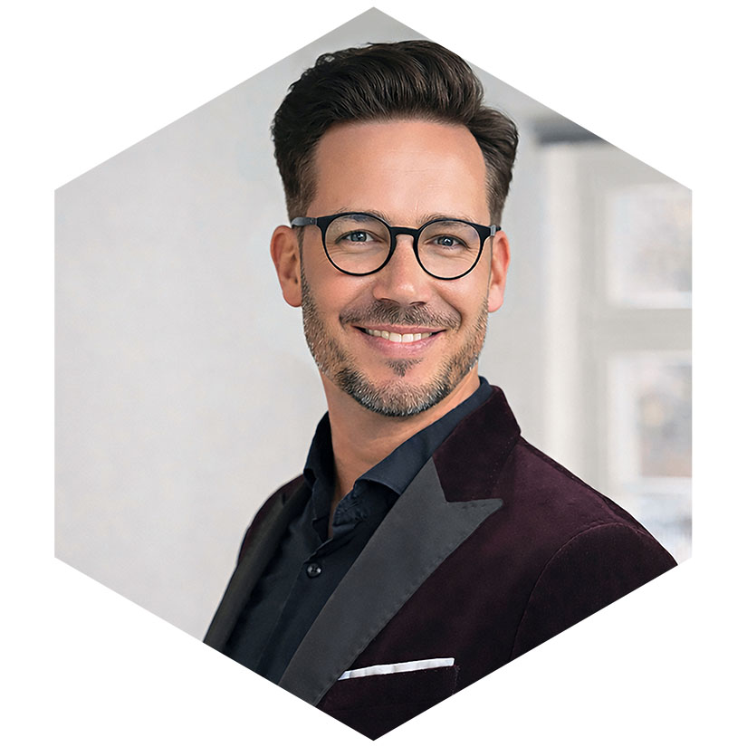 Porträt von Gunnar Mothes mit Brille und dunkelrotem Samtsakko, grafisch eingefasst in einem modernen Hexagon-Design, Creative Director & Senior Consultant für Coporate Designs, Corporate Identity, Kampagnen und Kreation bei WeichertMehner