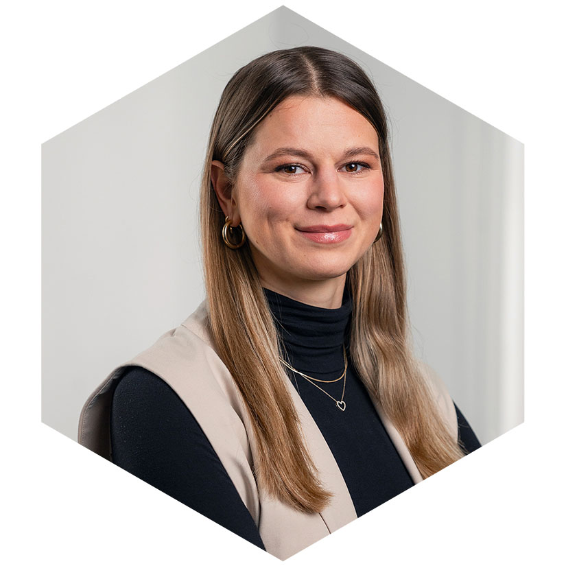 Porträt von Katharina Mehner mit schwarzem Rollkragenshirt und beige Weste vor hellem Hintergrund, grafisch eingerahmt in einem modernen Hexagon-Design, Beraterin für strategische Kommunikation und Corporate Communications bei WeichertMehner