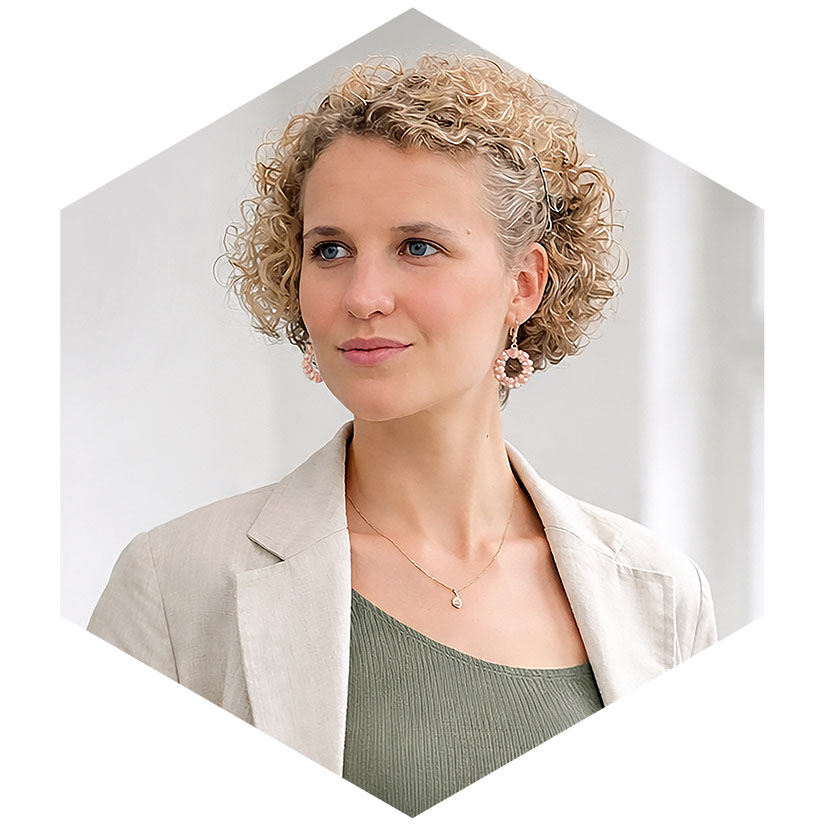 Porträt von Lilith Diringer in hellem Blazer und grünem Oberteil, präsentiert in einem modernen hexagonalen Grafik-Rahmen von WeichertMehner, Beraterin für strategische Kommunikation und PR bei WeichertMehner