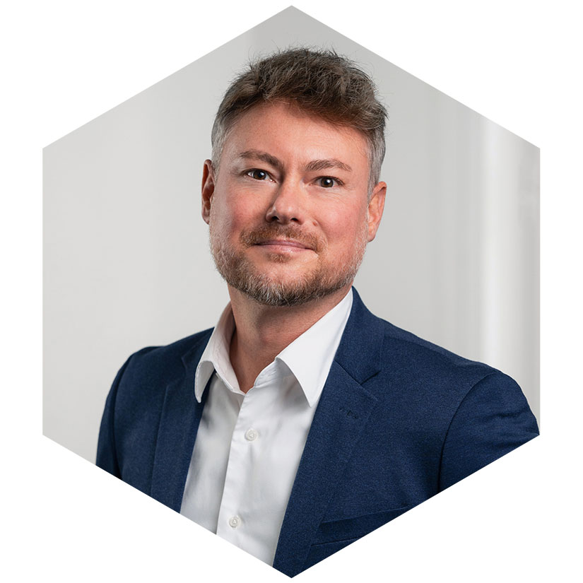 Porträt von Mathias Rentsch m blauen Sakko und weißem Hemd, dargestellt in einem hexagonalen Grafik-Element, Senior Berater für strategische Kommunikation und Krisenberatung bei WeichertMehner