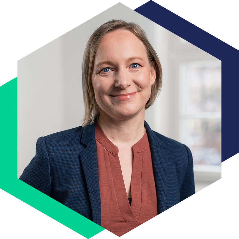 Porträt von Steffi Petersen im dunkelblauen Blazer und rostbraunem Oberteil, eingefasst in das hexagonale Corporate-Design-Element, Art Director bei WeichertMehner